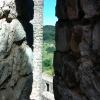 Arrowslit in Pombal Castle, Portugal. Narrow opening on castle wall allowing archers to shoot on the enemy from a sheltered vantage point. Through this arrowslit one can see the edge of another tower and the hills in the distance. 