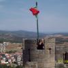 Castle of Bragança. Round granite tower with crenellations. Tower has the Portuguese flag and a lady watching through the crenellations. [By courtesy of Luisa Cabrita]